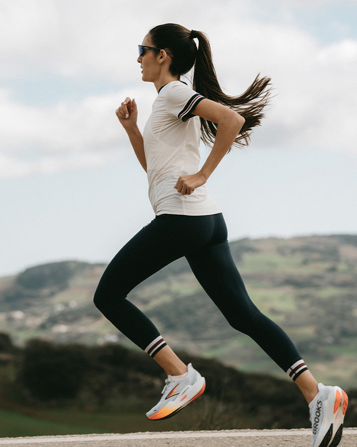 Mujer corriendo con mallas deportivas elásticas